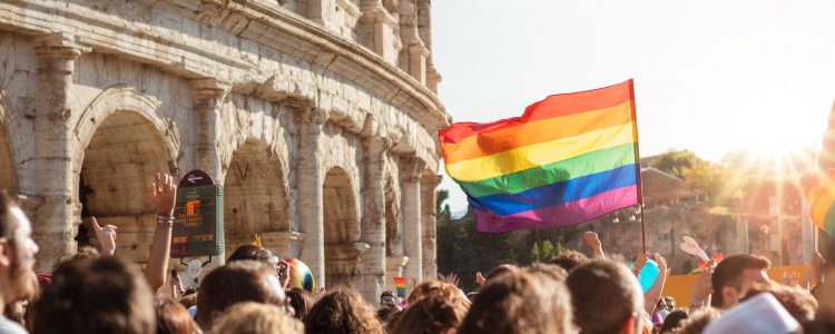 Group of people in Rome, Italy walking with rainbow Pride flag