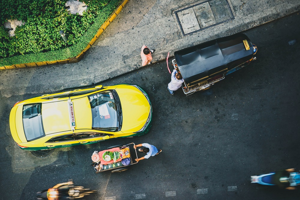 Birds eye view of a street in Bangkok with cars and motorbikes moving quickly