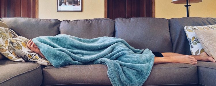 Person sick with flu lying on the sofa under a blanket