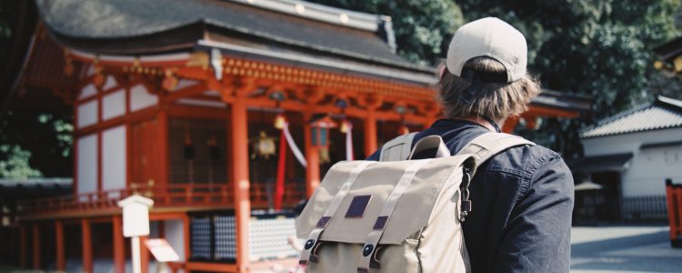 A man standing alone in front of a traditional building in Asia