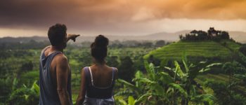 Couple looking across forest in Bali at sunset