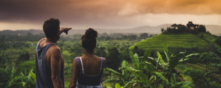 Couple looking across forest in Bali at sunset