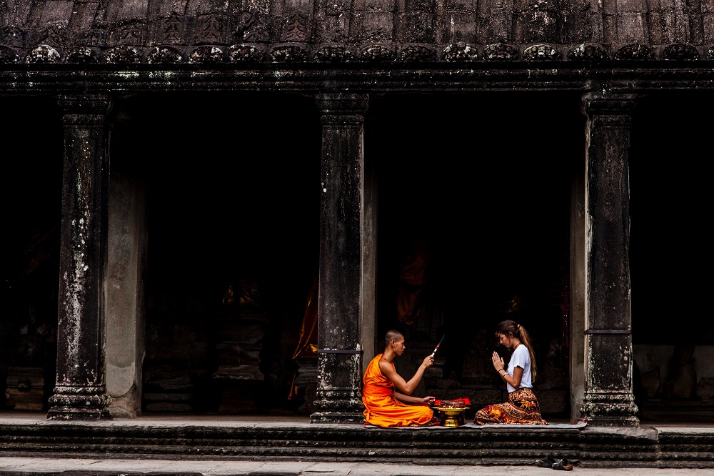 Western woman sitting praying with an buddhist monk