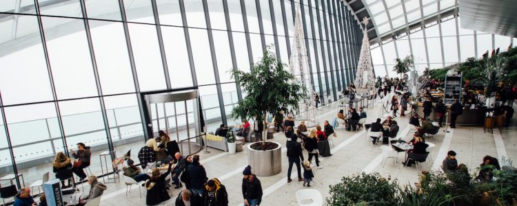 Busy airport with large windows and people walking to catch flights and waiting