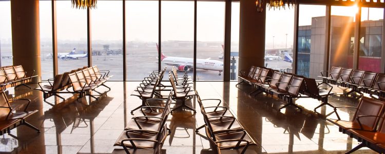 An airport waiting area with decorative lighting and large windows looking over planes