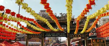 Busy street suring a Chinese festival with lanterns strung above the crowd