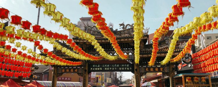 Busy street suring a Chinese festival with lanterns strung above the crowd