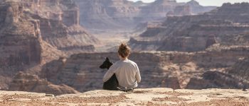 Woman sitting with dog above a canyon