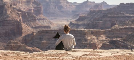 Woman sitting with dog aove a canyon