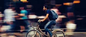 Man cycling quickly on a busy street in Asia