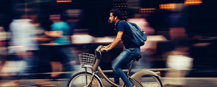 Man cycling quickly on a busy street in Asia