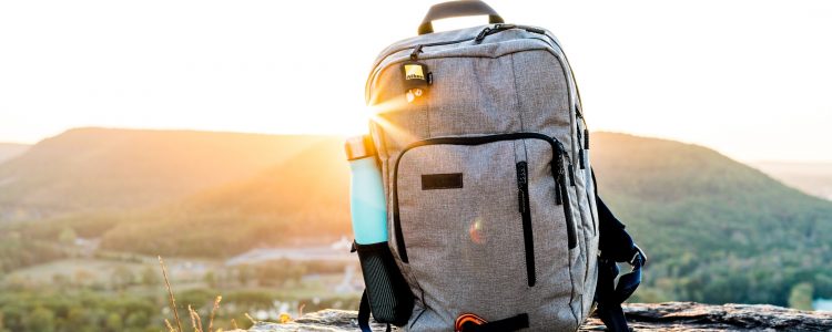 Backpack and water bottle with a sunset behind