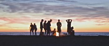 People around a fire on a beach at sunset