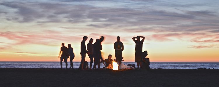 People around a fire on a beach at sunset