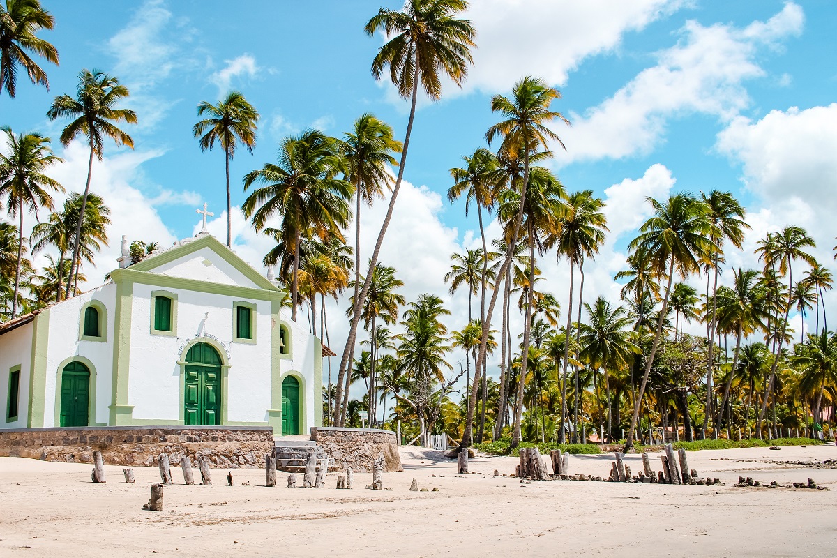 White church on a beach in Brazil with palm trees around