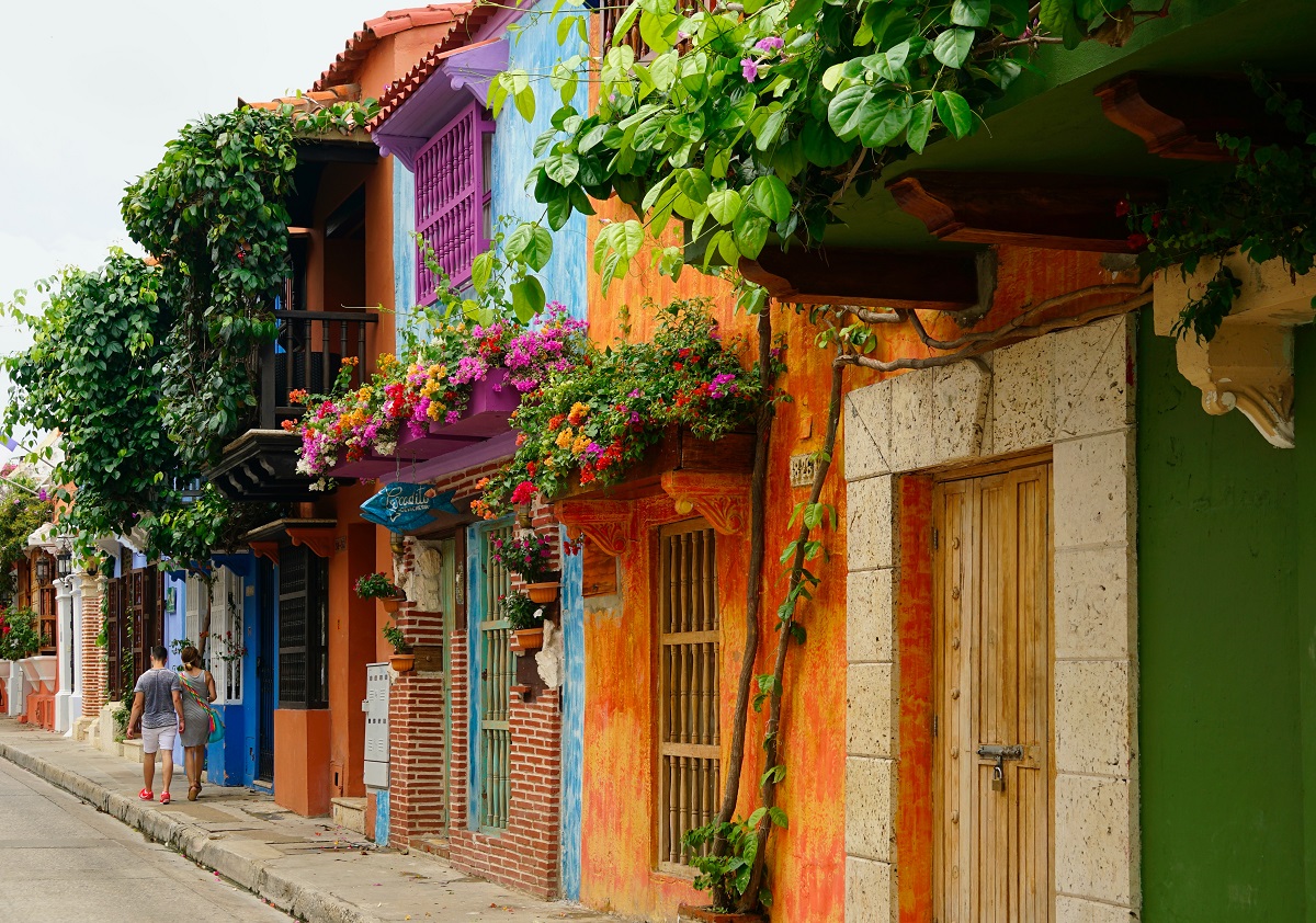 Brightly coloured houses covered in plants on a street in Colombia