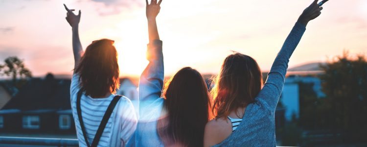 Three happy women looking at the sunset