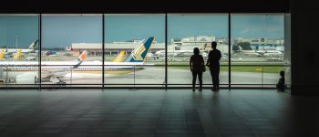Couple looking at planes through a window at anan airport